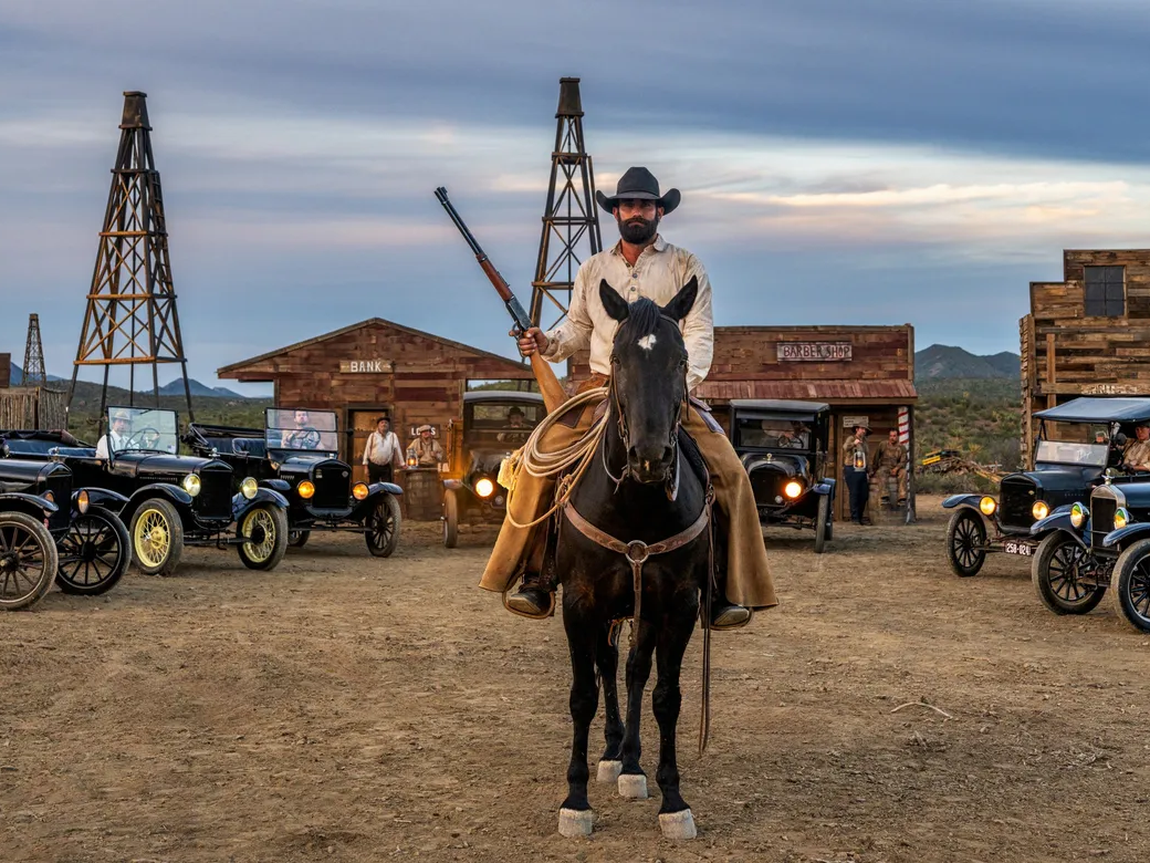 Boom Town by David Yarrow – Fine Art Color Photograph of Cowboy and Vintage Cars in Wild West – Available at Hilton Contemporary Gallery Chicago