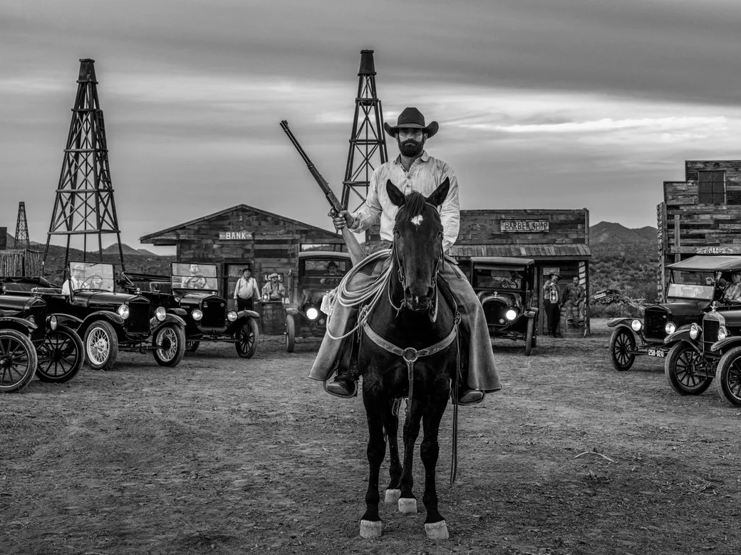 Boom Town by David Yarrow – Fine Art Photograph of Cowboy and Vintage Cars in Wild West – Available at Hilton Contemporary Gallery Chicago