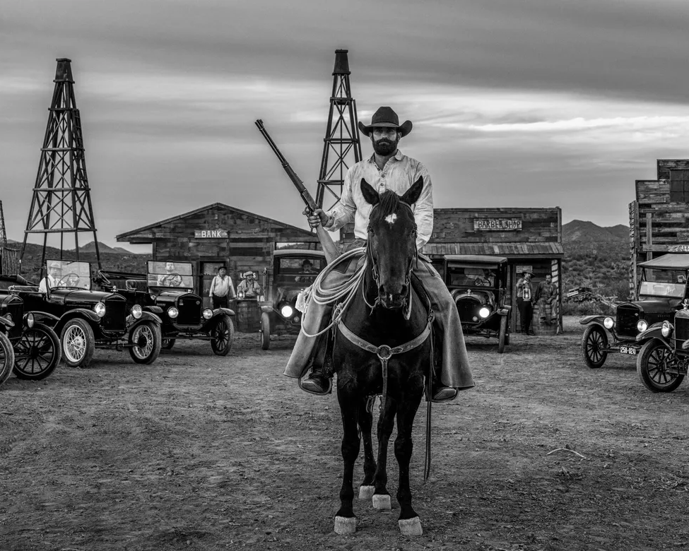 Boom Town by David Yarrow – Fine Art Photograph of Cowboy and Vintage Cars in Wild West – Available at Hilton Contemporary Gallery Chicago