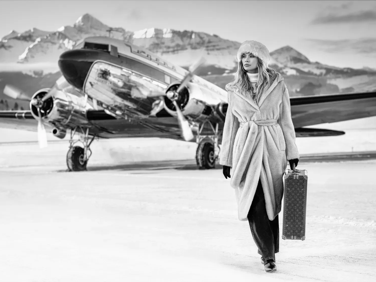 Winter Wonderland by David Yarrow – Fine Art Photograph of a Model Carrying Louis Vuitton Suitcase in Front of a Private Jet – Available at Hilton Contemporary Gallery Chicago