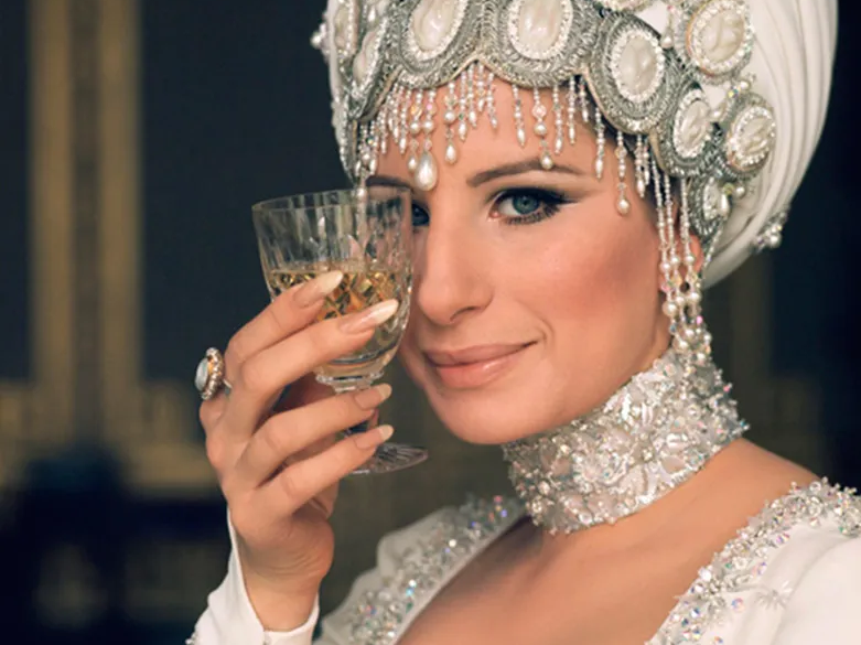Barbra Streisand wearing an ornate jeweled headdress and holding a glass, photographed by Lawrence Schiller, 1969