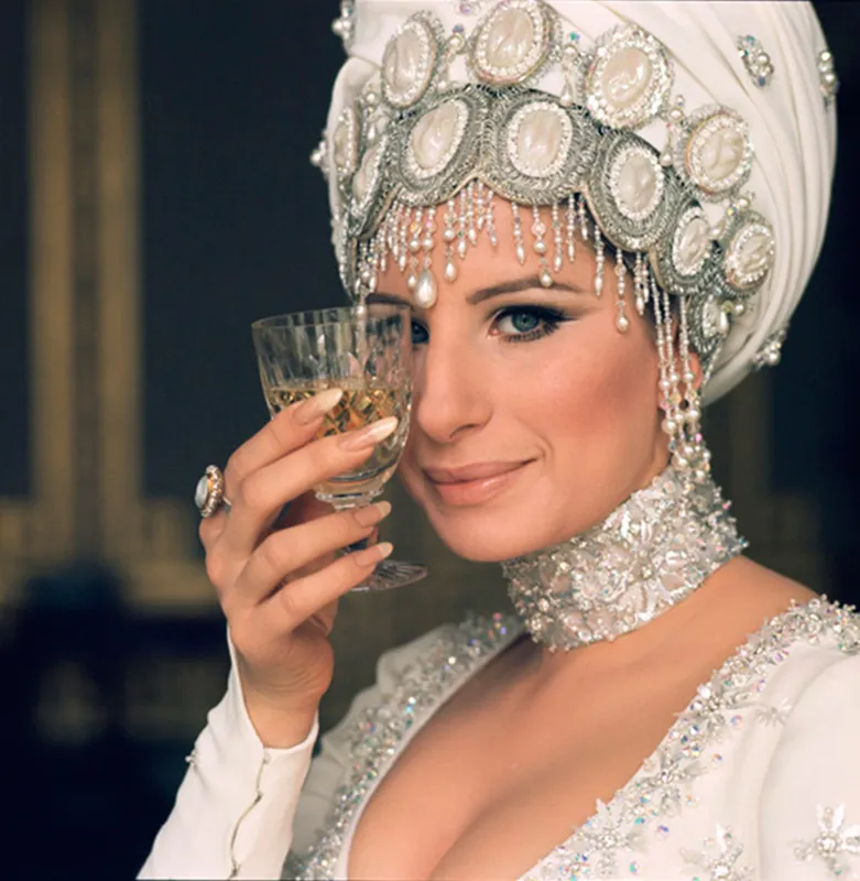 Barbra Streisand wearing an ornate jeweled headdress and holding a glass, photographed by Lawrence Schiller, 1969