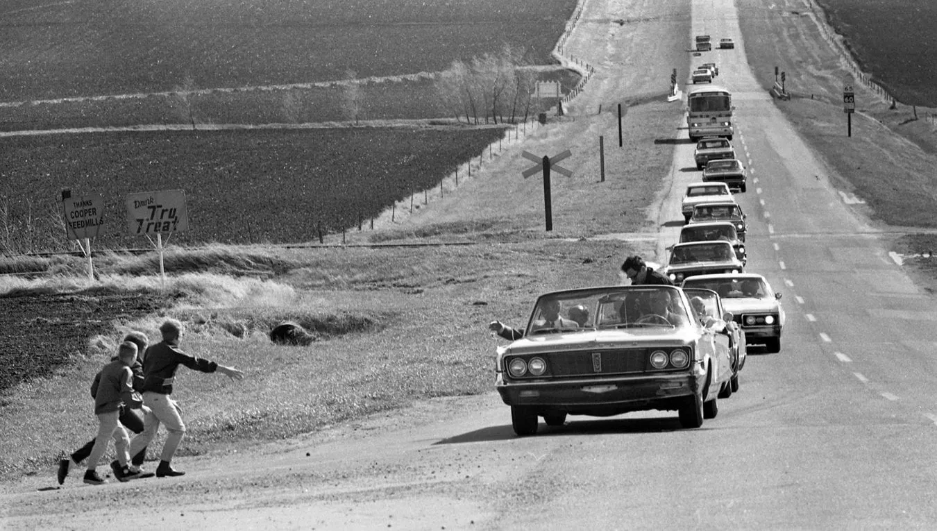 Robert F. Kennedy campaigning in 1968, greeting supporters from his car during the U.S. presidential race