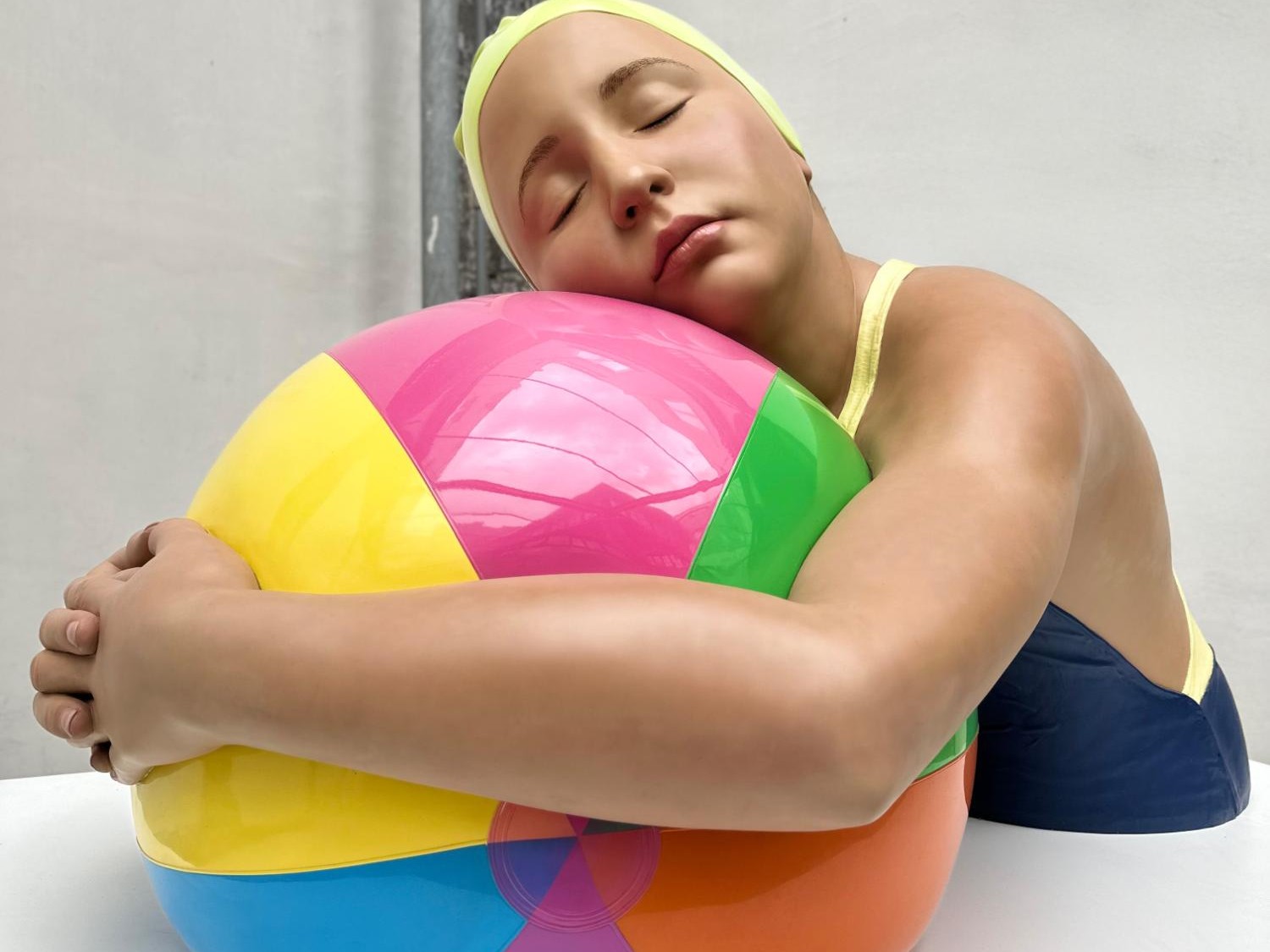 Brooke with Beach Ball. A hyper-realistic sculpture by Carole Feuerman. Lacquer on Resin with Painted Yellow Cap. Monumental Scale. 42 x 64 x 44 inches.