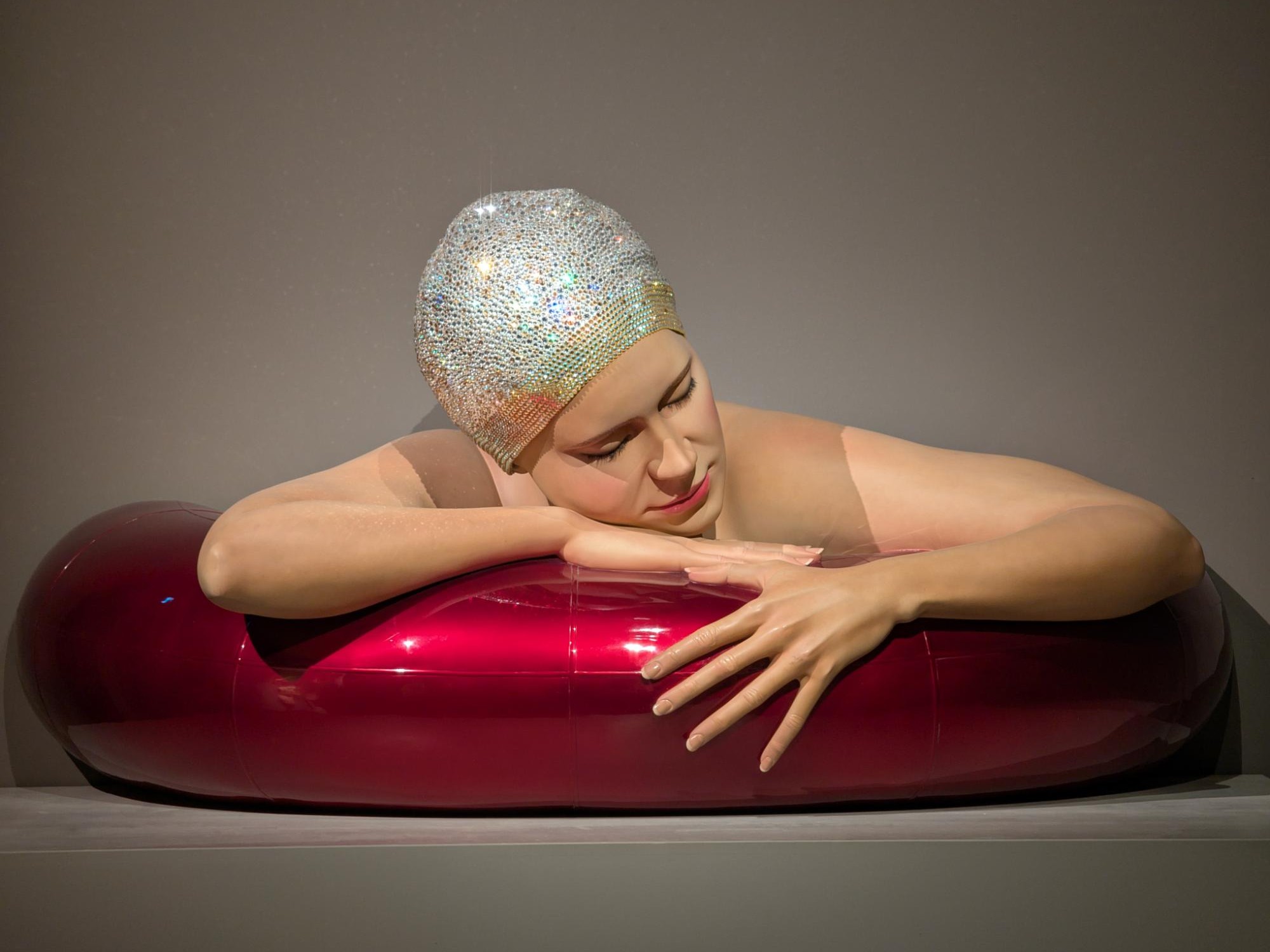 Survival of Serena with Candy Red Tube. A hyper-realistic sculpture by Carole Feuerman. Lacquer on Resin with Citrine AB Mosaic Crystal Cap. Monumental Scale. 38 x 84 x 32 inches.